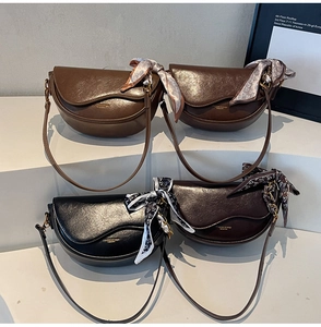 Three colors of faux leather saddle bags with decorative scarves on tiered display
