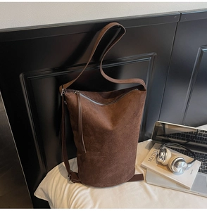 Detail of dark brown suede hobo bag with silver zipper and premium leather texture