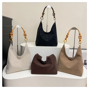 Détail de sacs cabas bohèmes en daim avec anses en perles de bois en quatre couleurs
