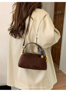 Retro brown suede Boston bag styled with a beige trench coat for a minimalist look