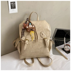 Close-up of beige vintage backpack with IBOME logo, buckles, and cute plush bear charm