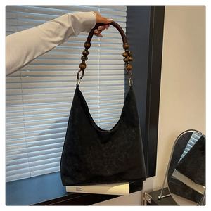 Detail of black tote bag featuring retro wooden beaded handles and matte finish suede texture