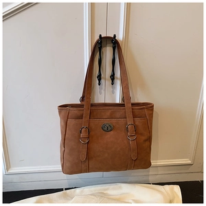 Detail of a brown retro tote bag with adjustable shoulder straps and metal twist lock closure