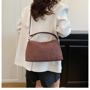 Detail showing high-quality dark brown suede texture and golden metal hardware of the tote