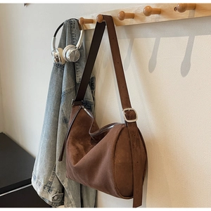 Detail of brown suede hobo bag with adjustable wide strap and silver metal buckle