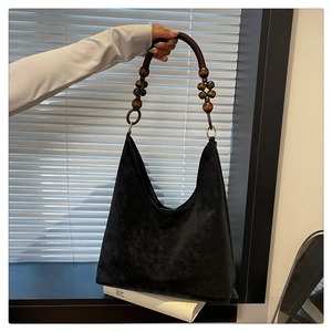Detail of a black matte tote bag featuring vintage dark brown wooden bead shoulder straps