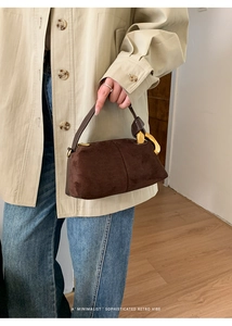 Close-up of brown suede Boston bag featuring a unique gold geometric metal buckle