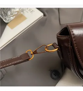 Close-up of premium dark brown leather saddle bag with high-gloss gold hardware and stitching