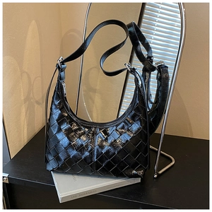 Nahaufnahme der schwarzen glänzenden gewebten Hobo-Tasche mit Fokus auf Textur und Zipper