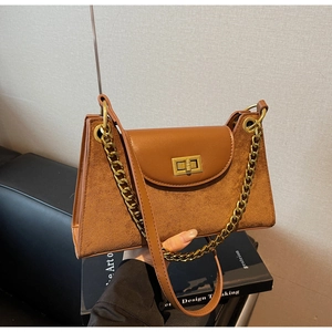 Detail of vintage brown shoulder bag showing textured suede and gold chain accents