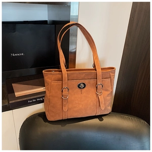 Detail of tan suede tote bag featuring silver twist lock and decorative white stitching