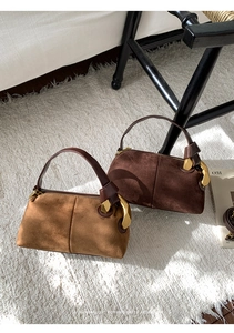 Detailed view of suede-textured pillow bags featuring large decorative gold metal buckles