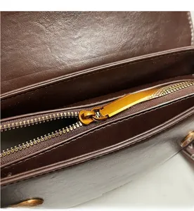 Close-up of smooth brass zipper on a premium brown textured leather shoulder bag