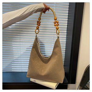 Detail of vintage beige tote bag featuring decorative wooden bead handles and matte texture