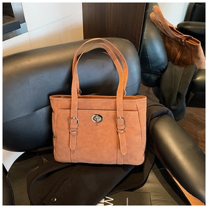Close-up of caramel tote bag featuring silver turn-lock closure and dual metal rings