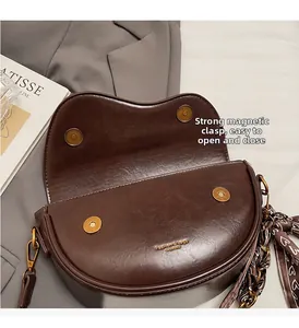 Detail view of brown saddle bag featuring magnetic closure and decorative scarf handle