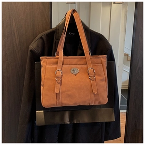Detail of a brown suede tote bag featuring a silver twist lock and visible stitching