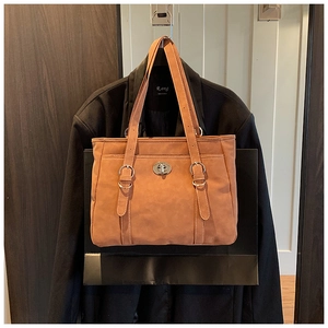 Detail of camel tote bag featuring white contrast stitching and silver twist lock buckle