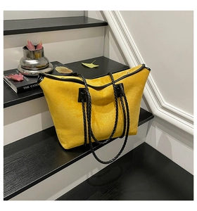 Detail of yellow suede tote bag featuring black woven handles and reinforced piping