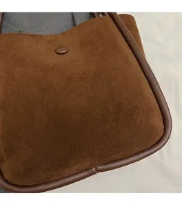Detailed macro shot of brown suede texture and decorative magnetic buckle on the bucket bag