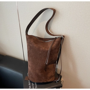 Detailed view of dark brown suede tote bag featuring long tassel zipper and wide shoulder strap
