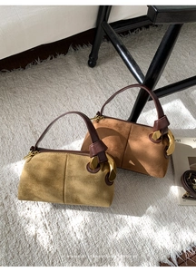 Detailed macro view of suede Boston bags with distinctive large gold semi-circular hardware