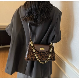 Close-up of leopard print suede crossbody bag with gold chain and metal twist lock