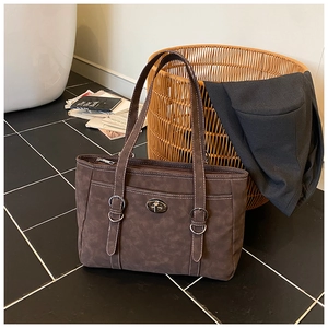 Close-up of brown suede tote bag featuring metallic turn-lock and vintage strap details
