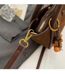 Detail of premium golden hardware and colorful wooden beads on brown suede bucket bag