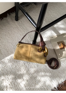 Close-up of yellow retro pillow bag with leather handle and gold hardware on white rug