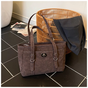 Detail of retro dark brown tote bag with suede texture and silver buckle on black tiles