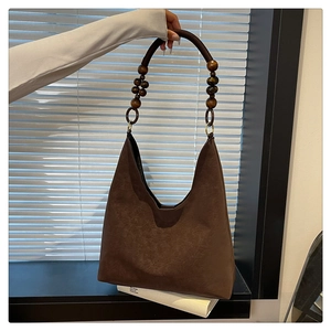 Detail of hobo bag with unique wooden beads and woven rope handle on dark brown suede