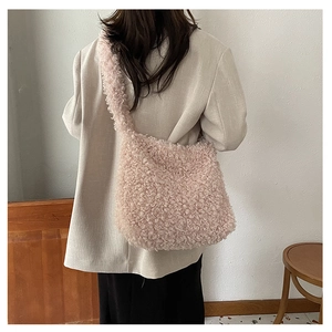 Detail of soft pink plush crossbody bag showing thick faux shearling texture on model