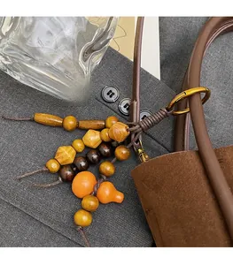 Detail of ethnic style handmade wooden beads pendant hanging on a dark brown bucket bag