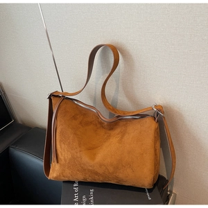 Detailed macro view of the brown suede handbag showing soft texture and silver zipper