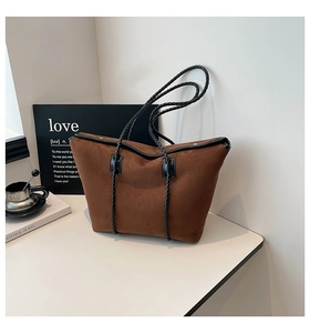 Brown suede tote bag with black woven straps shown in a minimalist aesthetic setting