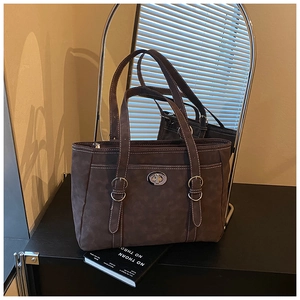 Detail view of large brown faux suede tote bag featuring silver twist lock and white stitching