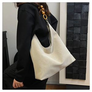 Detail of cream white tote bag featuring wooden bead accents and soft PU leather texture