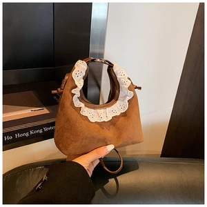 Detail of a brown suede mini handbag featuring elegant white double-layered lace handles