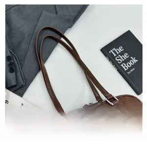 Detail view of smooth zipper closure and premium leather strap on deep brown tote bag