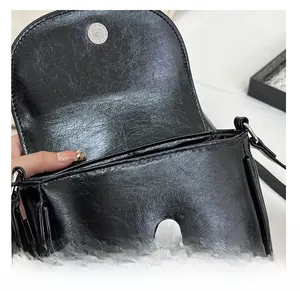 Detail of black faux leather saddle bag showing silver magnetic closure and interior opening