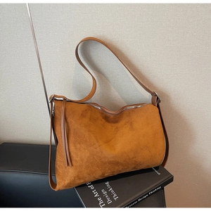 Detail of caramel suede shoulder bag with top zipper and slim leather straps