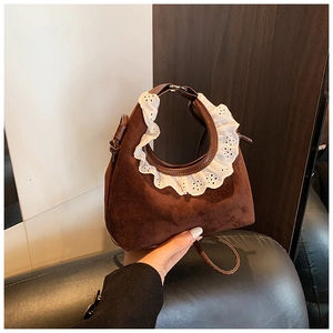 Detail of brown suede mini bag featuring white lace trim and dark leather shoulder strap