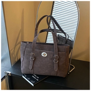 Detailed view of dark brown suede tote bag with silver twist lock and white stitching