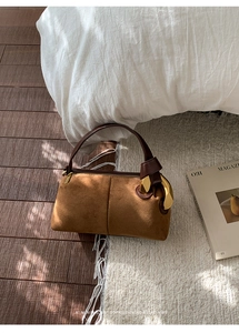 Detail of a brown suede Boston bag featuring a stylish gold geometric metal buckle