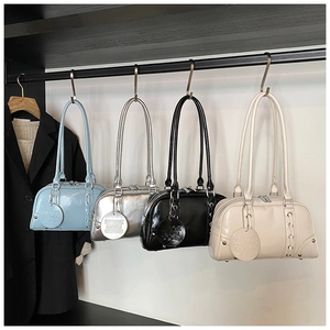 Detail of glossy minimalist bowling bag with lace-up side design and brand circular pendant