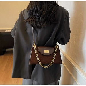 Detail of dark brown suede shoulder bag with gold chain strap and vintage twist lock