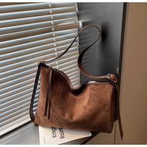 Detail of a dark brown suede crossbody bag with silver zipper and adjustable strap