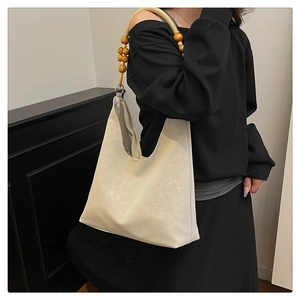 Detail of hobo bag featuring decorative wooden beads and premium cream faux leather texture