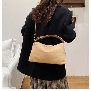 Detail of khaki suede tote bag styled on a shoulder with a black blazer